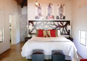 哈博罗内Waterside Cottages的卧室配有带红色枕头的大型白色床
