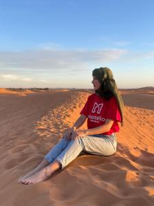 马拉喀什Miostello Lifestyle Hostel Marrakech的坐在沙漠沙上的女人