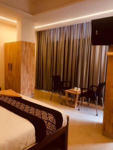 科泽科德RAINBOW ROOMS的酒店客房带一张床、一张桌子和椅子