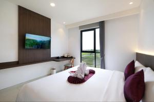 坎古ValStar Hotel Canggu的卧室配有白色床和紫色枕头