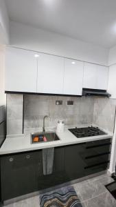 内罗毕Gatundu Heights的厨房配有白色橱柜、水槽和炉灶。