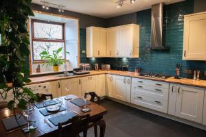 勒威克Stylish three-bedroom house in central Lerwick的厨房配有白色橱柜、木桌和用餐室