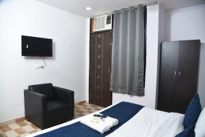 新德里Hotel Orchid INN at Budget Bazaar Janakpuri的一间卧室配有一张床、一把椅子和电视