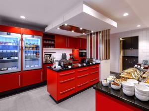 美因河畔法兰克福法兰克福城市会展中心阿德吉奥公寓酒店的一间厨房,配有红色橱柜和一个带食物的柜台