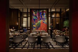 金泽Hyatt Centric Kanazawa的一间带桌椅的餐厅,以及一幅大画