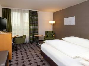 纽伦堡纽伦堡机场瑞享酒店的酒店客房配有一张床、一把椅子和一台电视。