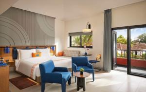 卡兰古特Ronil Goa - a JdV by Hyatt Hotel的酒店客房,配有一张床和两张蓝色椅子