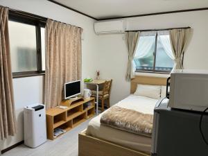 东京Bon House Kanamachi Direct to Sensoji Skytree Disneyland Airport Free Parking的一间卧室配有一张床和一张带电脑的书桌