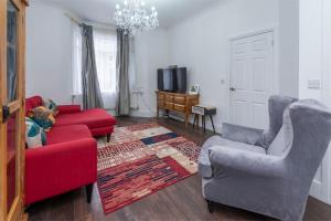 伦敦Stunning 3-Bed House的客厅配有红色的沙发和两把椅子