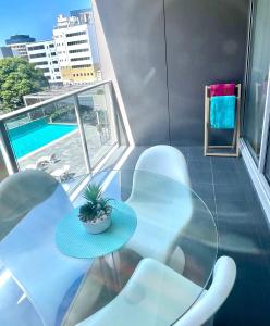 纽卡斯尔AQUA 306 POOLSIDE Luxury Apartment , Honeysuckle, NEWCASTLE FREE Parking的一个带桌椅的阳台和一个游泳池