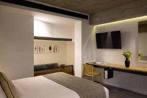 雅典雅典酒店的一间卧室配有一张床、一张书桌和一台电视。