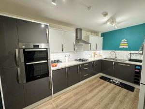 伍尔弗汉普顿Beautiful Home in Wolverhampton!的铺有木地板的厨房配有灰色家电