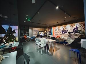 西安Sifang Space Hostel Xi'an - Xi'an KEJIDAXUE metro Line4的餐馆,有坐在桌子旁的人,还有一棵圣诞树