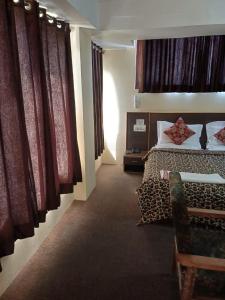 斯利那加Hotel Town Centre , Srinagar的一间卧室配有床、沙发和窗帘