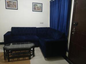 拉合尔Two Bedrooms Apartment Near DHA & Airport的客厅配有蓝色的沙发和桌子