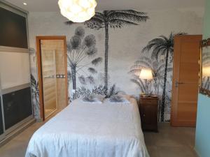 圣让德韦达Belle villa, piscine et cigales au calme !的卧室配有白色的床,墙上挂着棕榈树