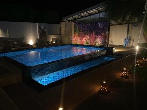 Ban Khlong Haeng3 Bedroom Platinum Pool Villa Smooth as Silk的夜间后院的游泳池,有蓝色的灯光