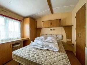 亨斯坦顿Superb Dog Friendly Caravan With Decking In Hunstanton In Norfolk Ref 13010l的一间卧室配有带白色床单和枕头的床。