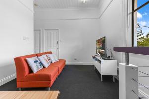 布里斯班Private Windsor House Studios Apartment的客厅配有橙色沙发和电视