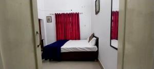 阿拉哈巴德BAGEECHA VILLA的一间小卧室,配有红色窗帘