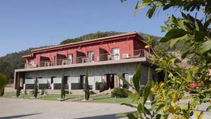 坎塔卢普斯Hostal Rural Can Pau的一座红色的建筑,上面设有一个阳台