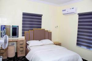 EgbaCozy Urban Oasis 3 Bedroom in Ogba, Ikeja, Lagos的一间卧室配有一张床和一张带电脑的书桌