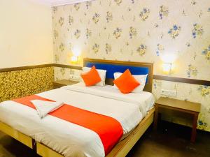 海得拉巴The City Park hotel的一间卧室配有带橙色和白色枕头的床