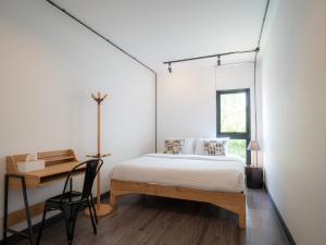 清迈Ombra House No. 21-24的一间卧室配有一张床、一张书桌和一个窗户。