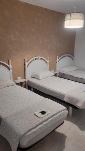 卡尔达斯·德·雷斯ALBERGUE de Caldas de Reis URRACA的在酒店客房的两张床,上面有手机