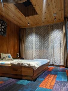 HoatHOMESTAY ĐỐM HOUSE的卧室配有一张床铺,位于带木墙的房间内