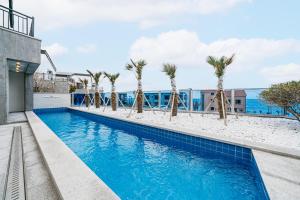济州市Ddosi Aewol Pool Villa的一座棕榈树游泳池,位于酒店大楼旁