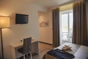 瓦拉泽Hotel Villa Centa的酒店客房配有一张床、一张书桌和一台电视。