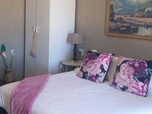 GrünauVastrap Guest Farm的一间卧室配有一张带粉色和紫色枕头的床