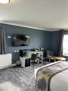 圣艾夫斯Dolphin Hotel Cambridge的一间卧室配有一张床、一张书桌和一台电视。