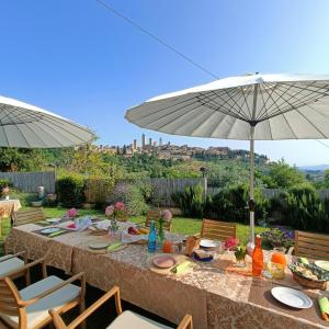 圣吉米纳诺B&B Il Fienile San Gimignano的餐桌,带食物盘和雨伞