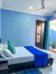 NilandhooHide Inn Blue的蓝色墙壁间的一张床位