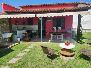 萨夸雷马Casa da Dinda à 650m da praia de Itaúna的院子里的红色房子,配有桌椅