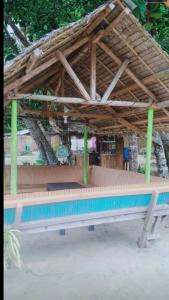 BacunganA&Z Nagtabon Lodge的一个带木屋顶和长凳的游泳池