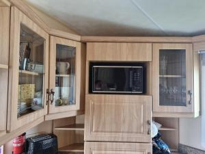 赫彻姆Dog Friendly Caravan Heacham Norfolk Holiday的厨房配有木制橱柜和微波炉。