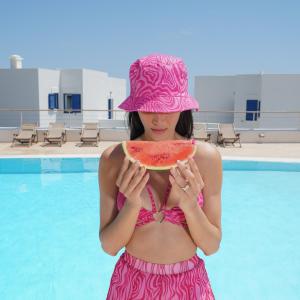 卡普萨利奥埃尔索尔酒店的戴着粉色帽子的女人,拿着西瓜片