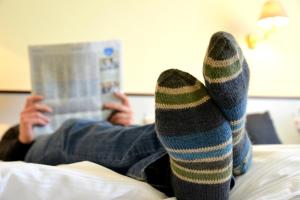 吕贝克阿尼姆斯赫伽尼酒店的穿着条纹袜子在床上读书的人