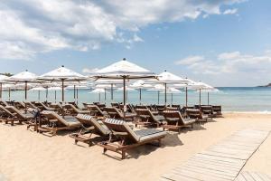 雅典Vouliagmeni Garden Suite by Astir beach的海滩上的一组椅子和遮阳伞