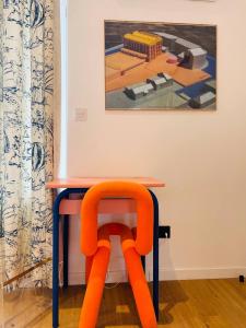 图尔昆Maison Georges的画前的一张桌子和一张橙色椅子