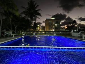 嘎林海斯港Charmante Maison dans residence Privé Tropicaliente prés de Porto de Galinhas的城市的一座大型游泳池,晚上有蓝色的灯光