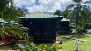 刁曼岛Nazri's Place 2的一座黑色房子,拥有绿色的屋顶和棕榈树