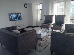 蒙巴萨Siradi apartments的客厅配有3张沙发和1台电视