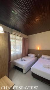 马六甲Lovita Tanjung Bidara Beach Resort的一间卧室设有两张床和窗户。