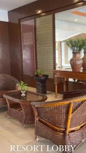 马六甲Lovita Tanjung Bidara Beach Resort的一间设有藤椅、桌子和镜子的客房