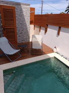 圣若瑟VILLA O'LHAYA piscine pivée的房屋设有游泳池、椅子、桌子和椅子