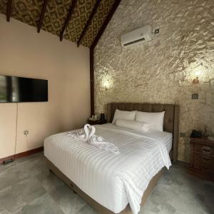 BanjarbaruNamira Paradise Garden的卧室配有一张白色大床和石墙